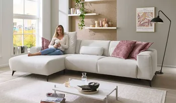 Frau sitzt auf gemütlichen weißem Sofa und entspannt.